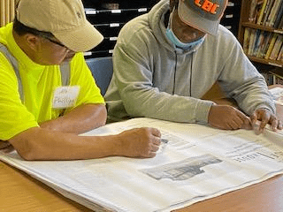 A plumbing teacher showing a student how to read blueprints